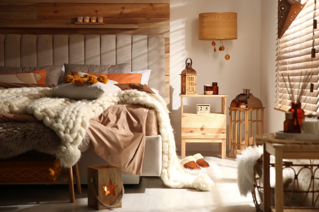 Cozy fall bedroom interior with knitted blanket and cushions